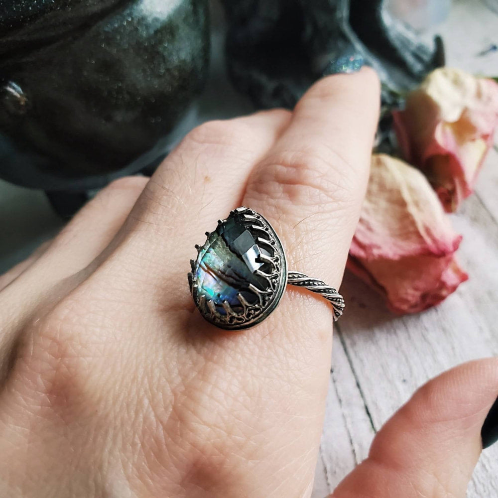a woman’s hand holding a ring with a black stone