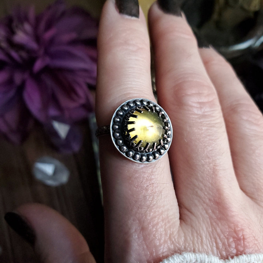 a woman’s hand holding a ring with a yellow stone
