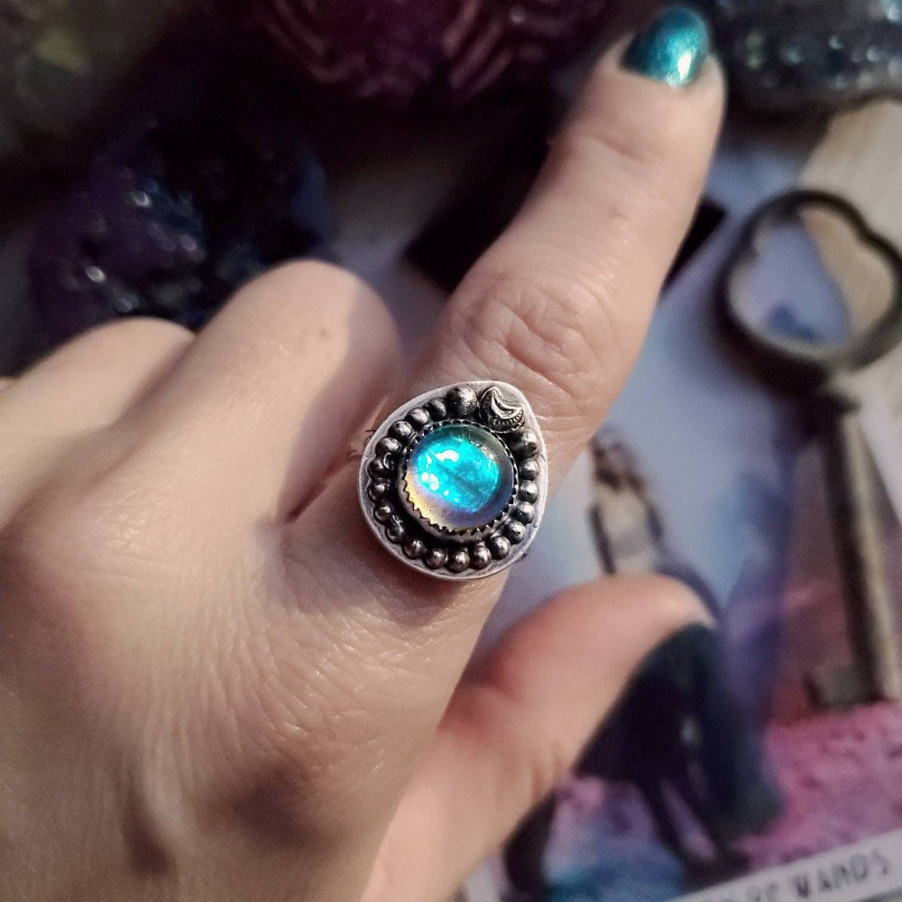 someone is holding a ring with a blue and green stone