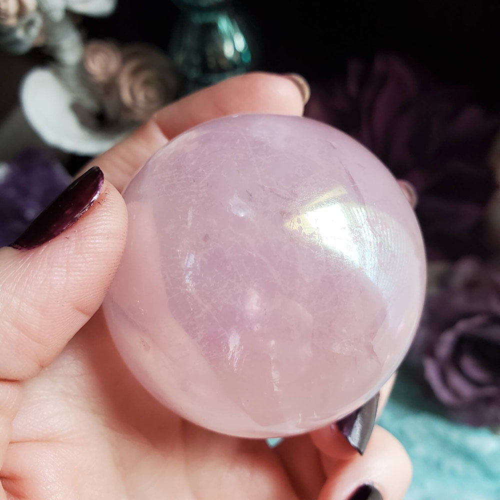 a person holding a pink quartz ball
