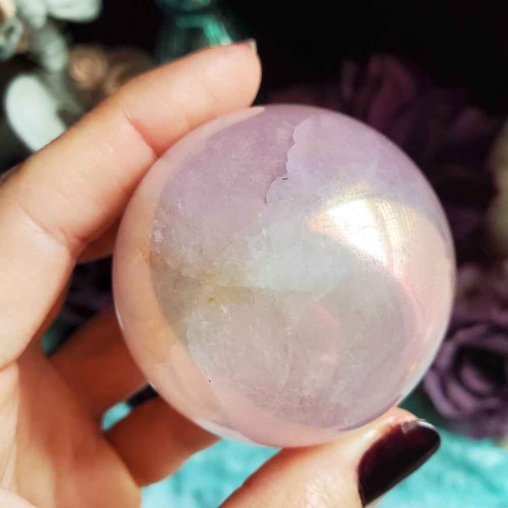 a person holding a large pink quartz ball