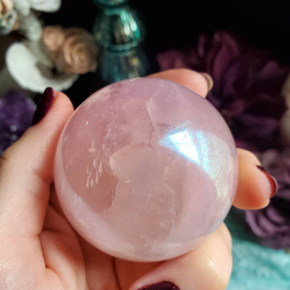 a person holding a pink quartz ball