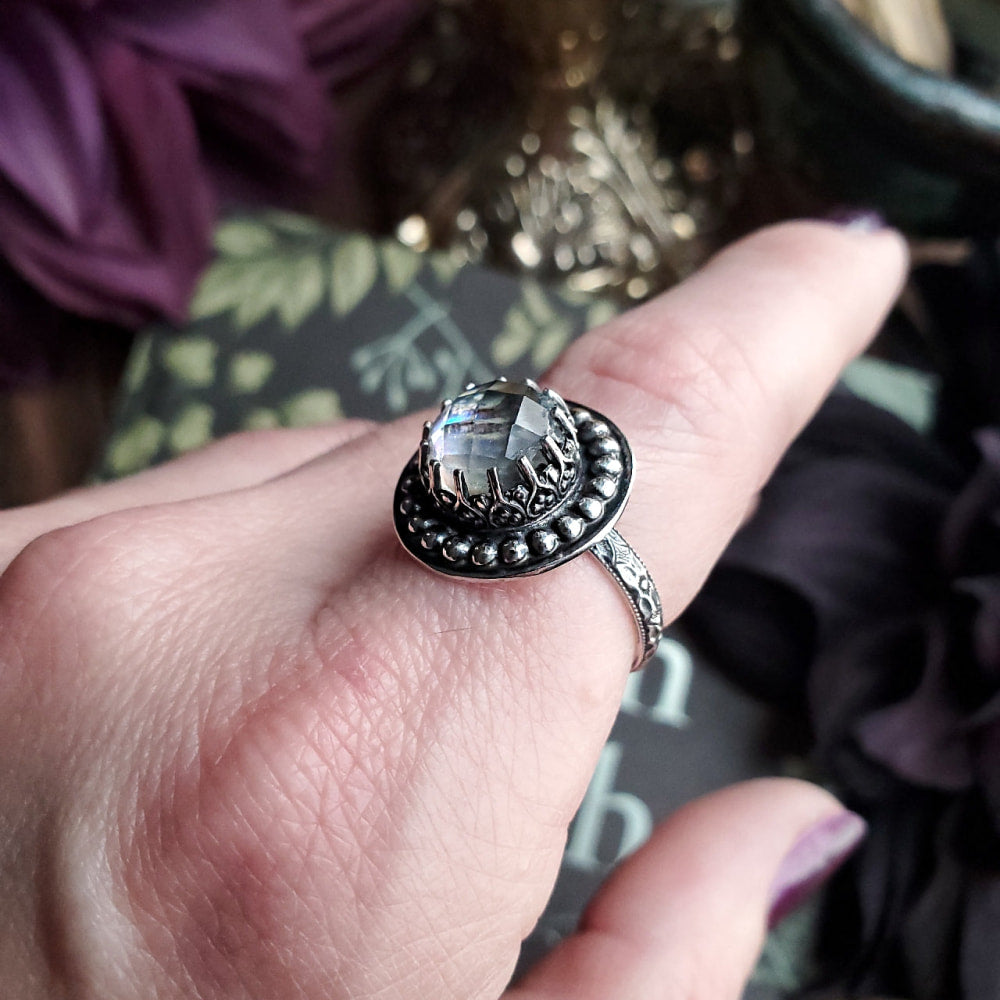 a woman’s hand holding a ring with a face