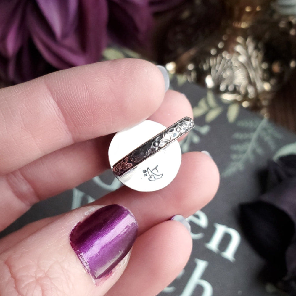 a person holding a purple nail with a ring on it