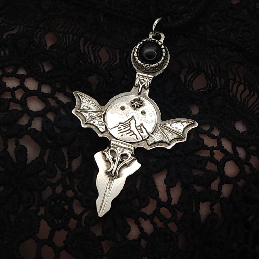 Silver bat-winged cross pendant with black stone.