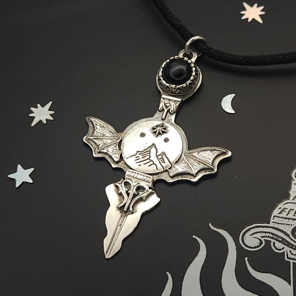 Silver bat-winged pendant with black stone.