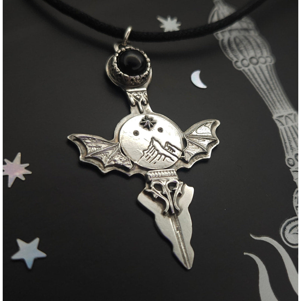 Silver bat-winged cross pendant.
