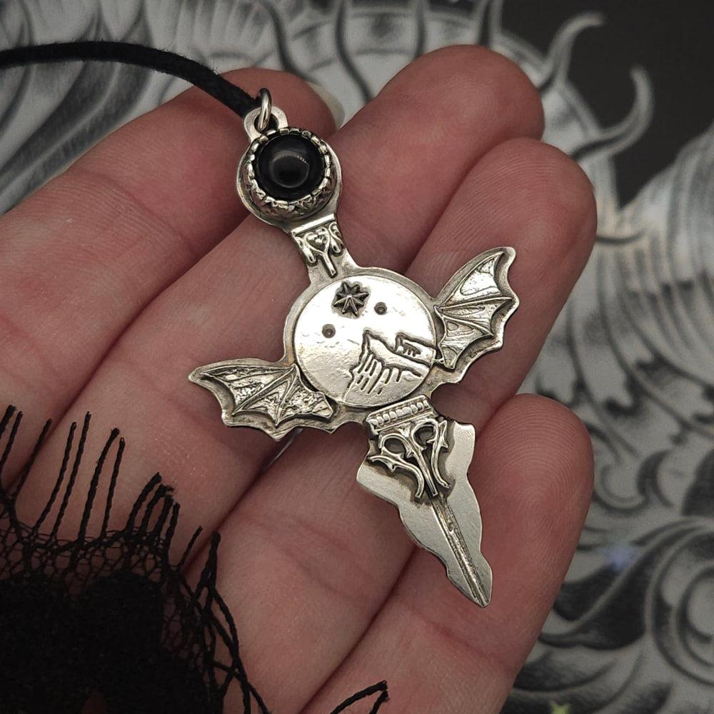 Silver bat-winged pendant with black stone.