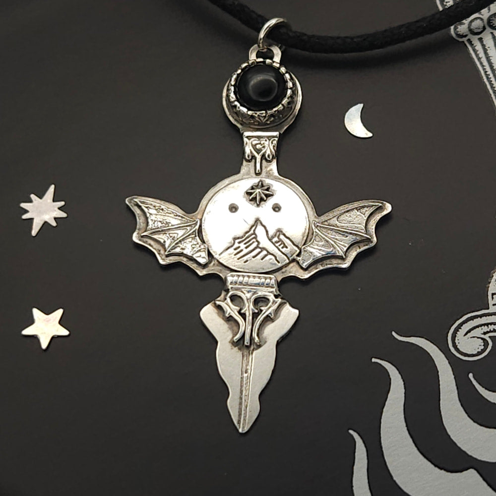 Silver bat-winged pendant with black stone.