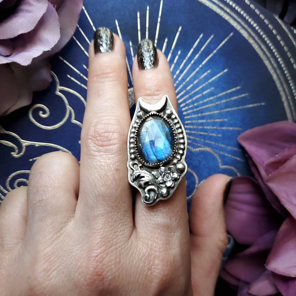 a woman’s hand holding a ring with a blue stone