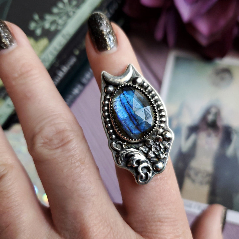 a woman’s hand holding a ring with a blue stone