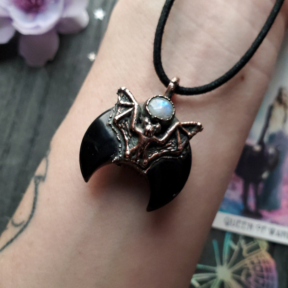 a bat pendant on a woman’s wrist