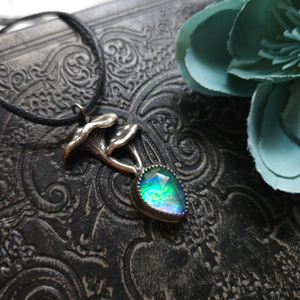 Pendant necklace featuring a mermaid figure holding an iridescent gemstone.