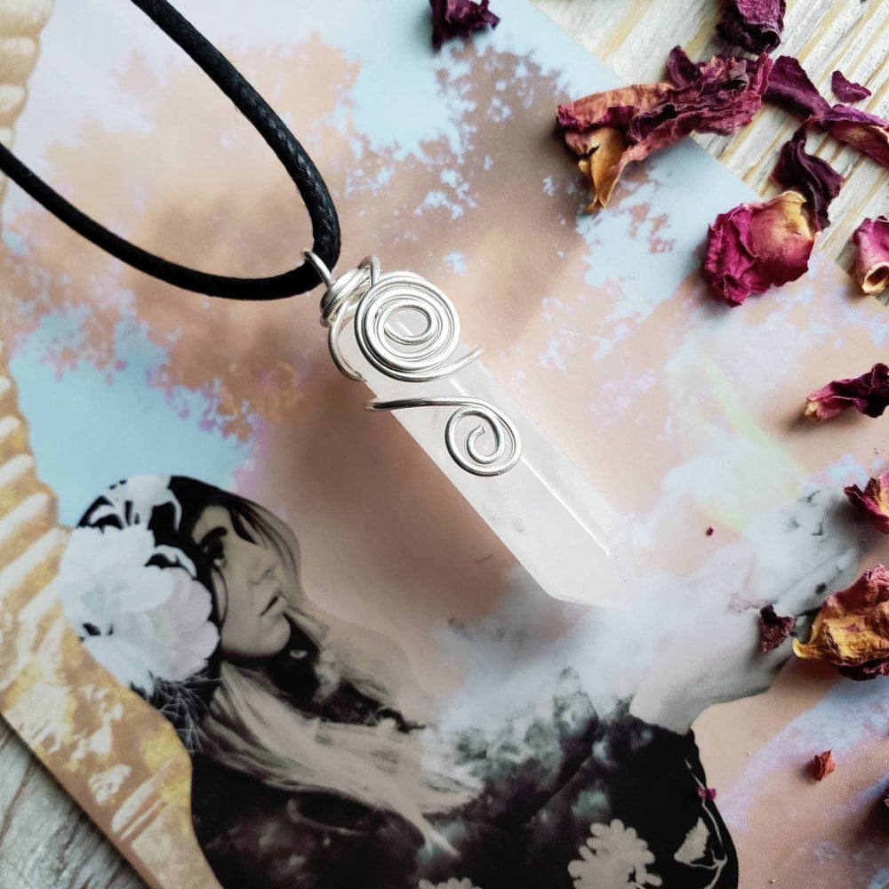 a white pendant with a black cord on a wooden table