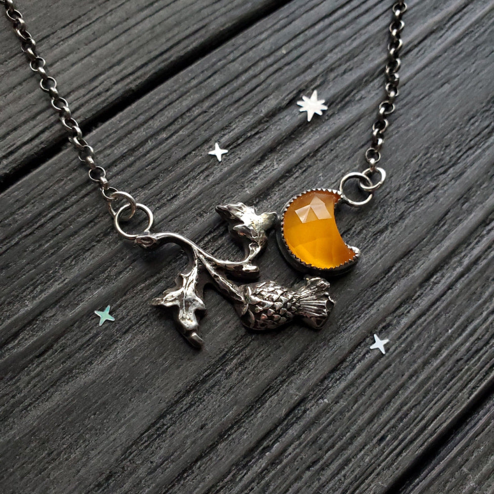 a silver necklace with a yellow glass and a silver star