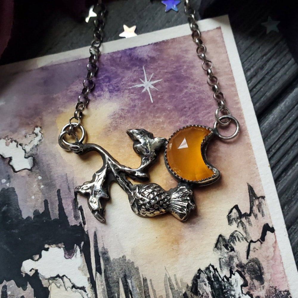 a necklace with a cat and a moon on it
