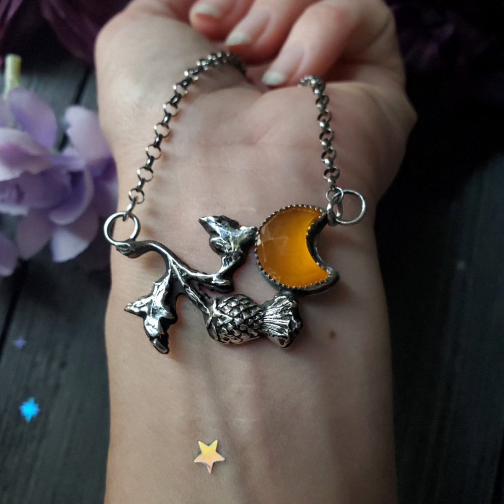 a person holding a bracelet with a dragon charm