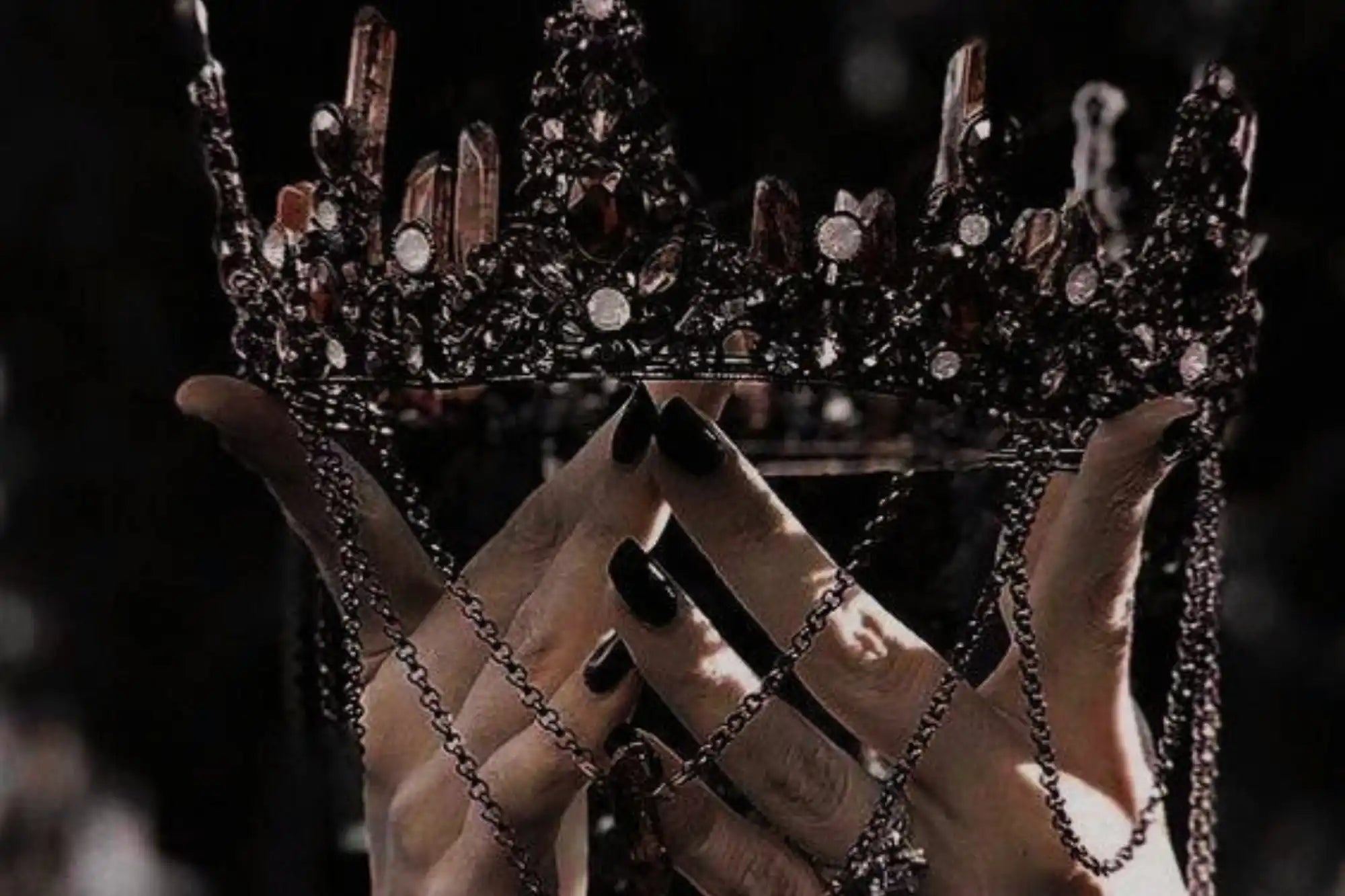 Dark, jeweled crown held by hands.