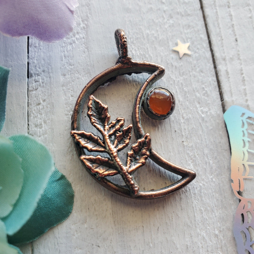 a copper moon with a branch and a star on it