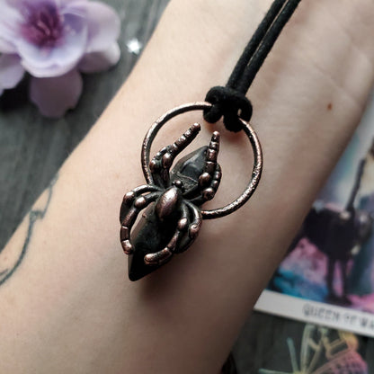 Spider-shaped pendant on a black cord necklace.